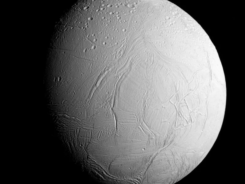 A bright white icy moon with long cracks and craters