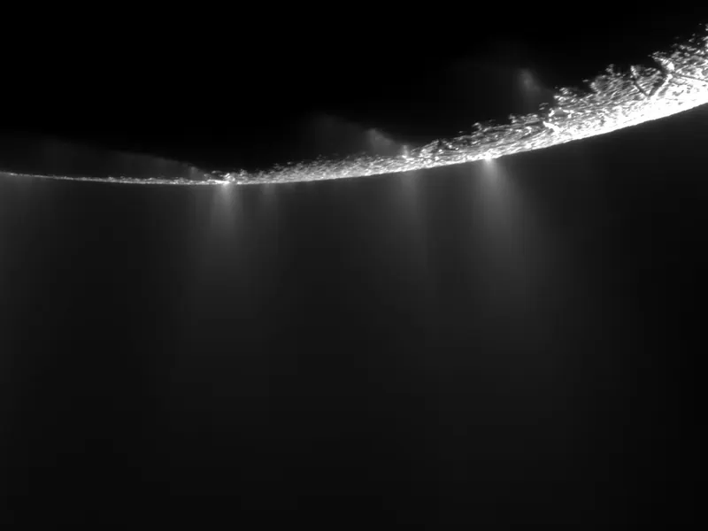 Jets of icy spray fanning out from the dark edge of a moon