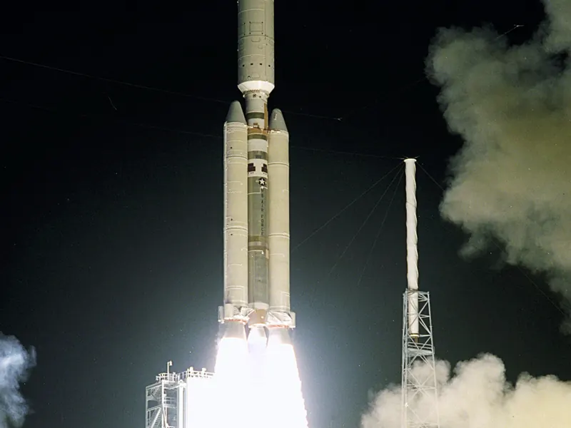 A rocket lifting off at night in a bright burst of flame